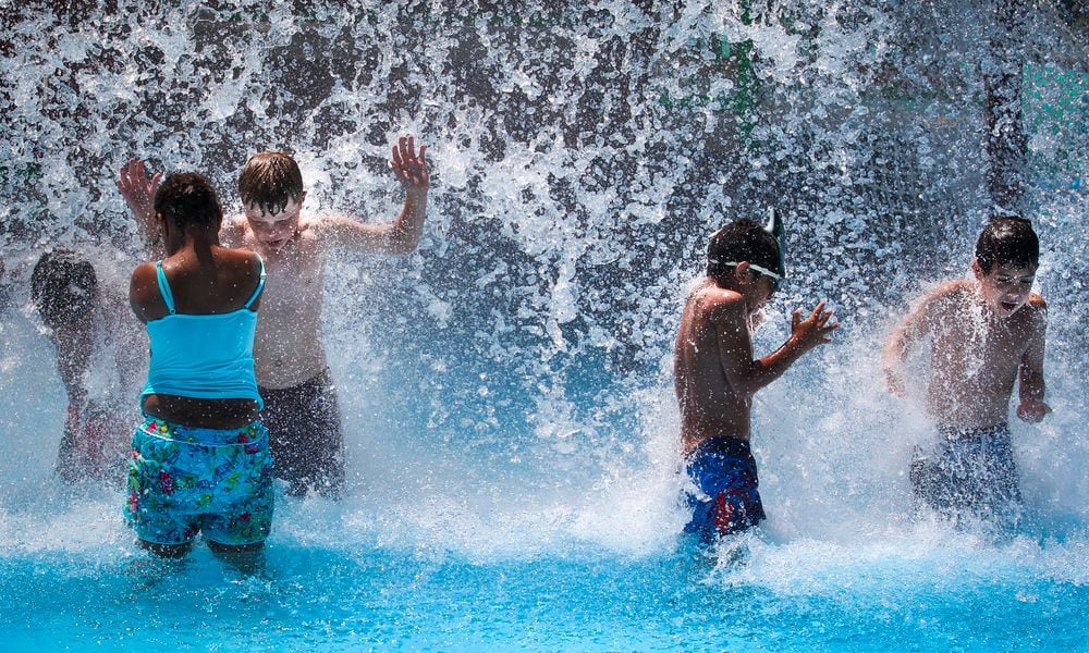 Children cool off under a waterfall at the Tipp City Family Aquatic Center. Highs will be in the low-90s, but the extreme humidity will push the heat index up. The real feel temperature is 100 degrees. JIM WITMER / STAFF
