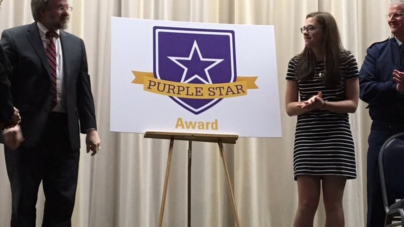 Paolo DeMaria, state superintendent for public instruction (left), and Zuza Livosky, 17, a Fairborn High School junior, unveil the new Purple Star Award in April 2017 at the National Museum of the U.S. Air Force. At far right is Maj. Gen. Mark E. Bartman, Ohio adjutant general. BARRIE BARBER/STAFF