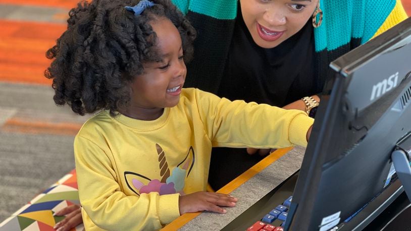 Chrissy Sanders and her daughter, Olivia, try out the technology at the new Dayton Metro Library Northmont Branch on Saturday. Chrissy serves as DML's finance director. AIMEE HANCOCK/STAFF