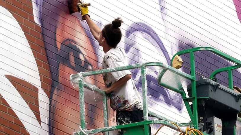 Muralist Gaia, from New York City, works on the mural of Springfield civil rights advocate Hattie Moseley on Thursday, Oct. 6, 2022 on the side of the WesBanco building in downtown Springfield. BILL LACKEY/STAFF