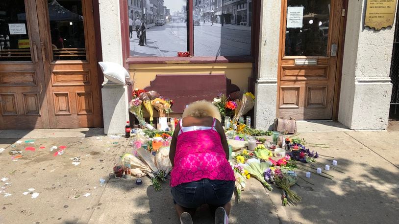 Annette Gibson-Strong cries in front of the memorial to the victims of the Oregon District mass shooting on Monday. She painstakingly moved the memorial so that Ned Peppers Bar could open that day. BONNIE MEIBERS/STAFF