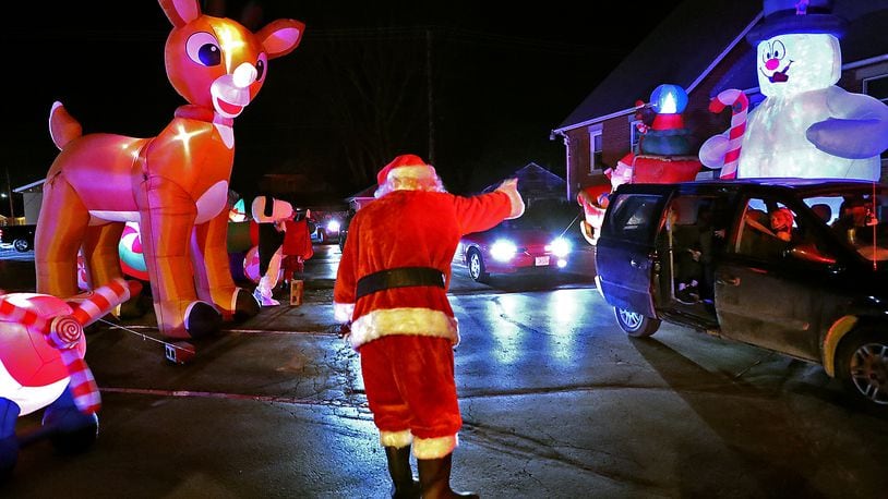 Santa waves to a van full of children Saturday during the New Carlisle Holiday Drive-thru reverse parade in downtown New Carlisle. BILL LACKEY/STAFF
