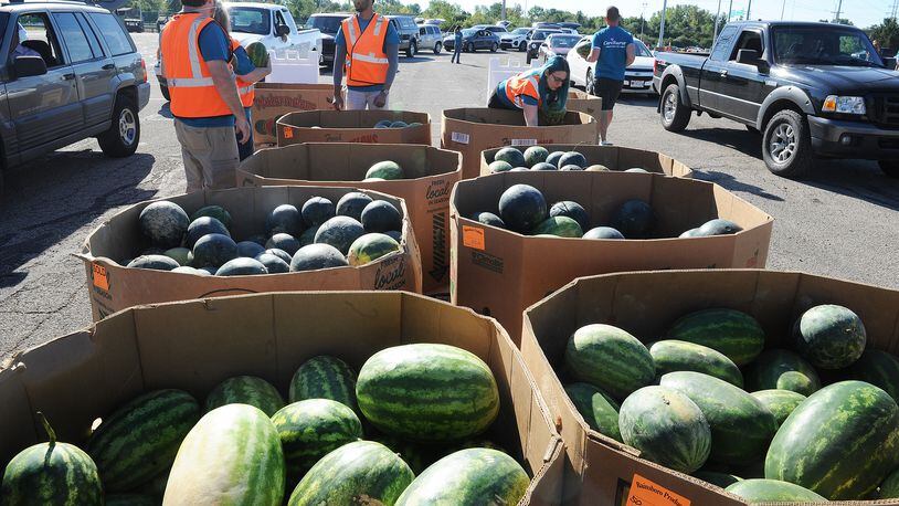 Volunteers handed out watermelons Thursday, Sept. 9, 2021, at the Dayton Food Bank mass food distribution at the Wright State University Nutter Center. MARSHALL GORBY\STAFF