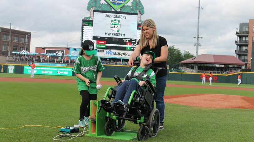 At the Dayton Dragons game Friday, May 17, 2024, Lola Zimmer (left), a student at Prass Elementary in Kettering, helped her friend Neil throw out the first pitch, using a device Lola and others made, as Neil's mom, Nikki looks on. Contributed photo, courtesy of Dayton Dragons