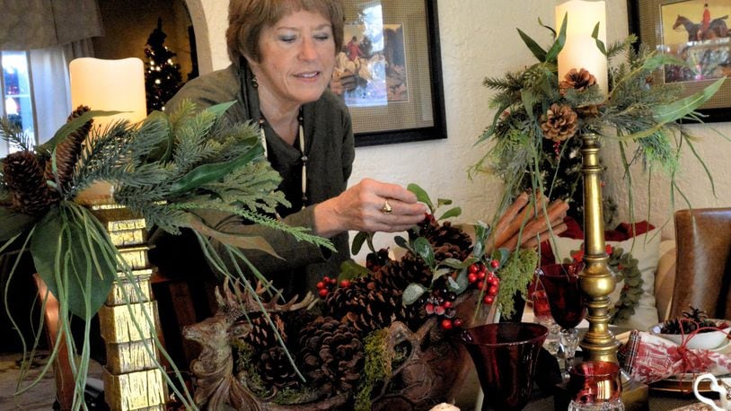 Diana Begley of Tipp City makes adjustments to her dining room table decorations in preparation for the 2015 Christmas in the Village home tour. CONTRIBUTED