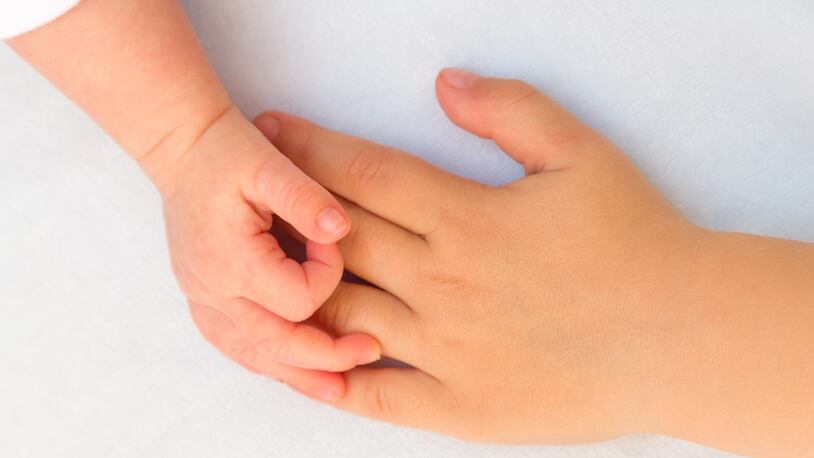 Child and baby holding hands (stock photo).